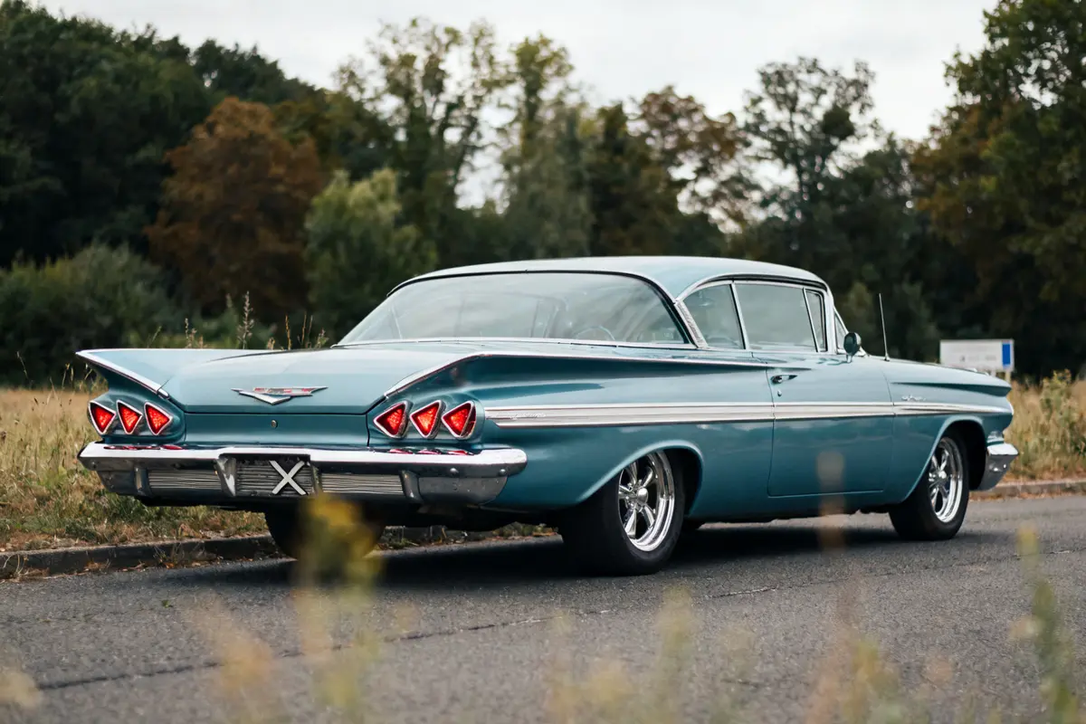 Chevy 1959 Impala bleu garé sur route devant forêt automnale