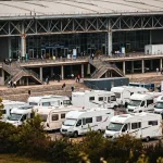 Park de camping-cars devant un grand bâtiment où se trouve le prochain salon du camping car
