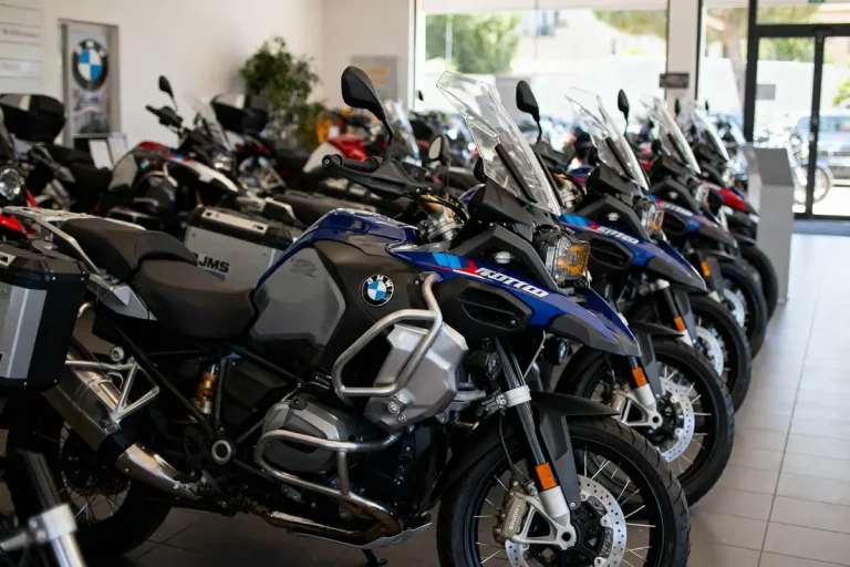 Salle d'exposition de motos BMW, alignées en rangée, avec pare-brise et accessoires visibles.