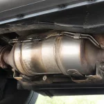 Vue sous un véhicule montrant un pot catalytique métallique attaché à l'échappement.