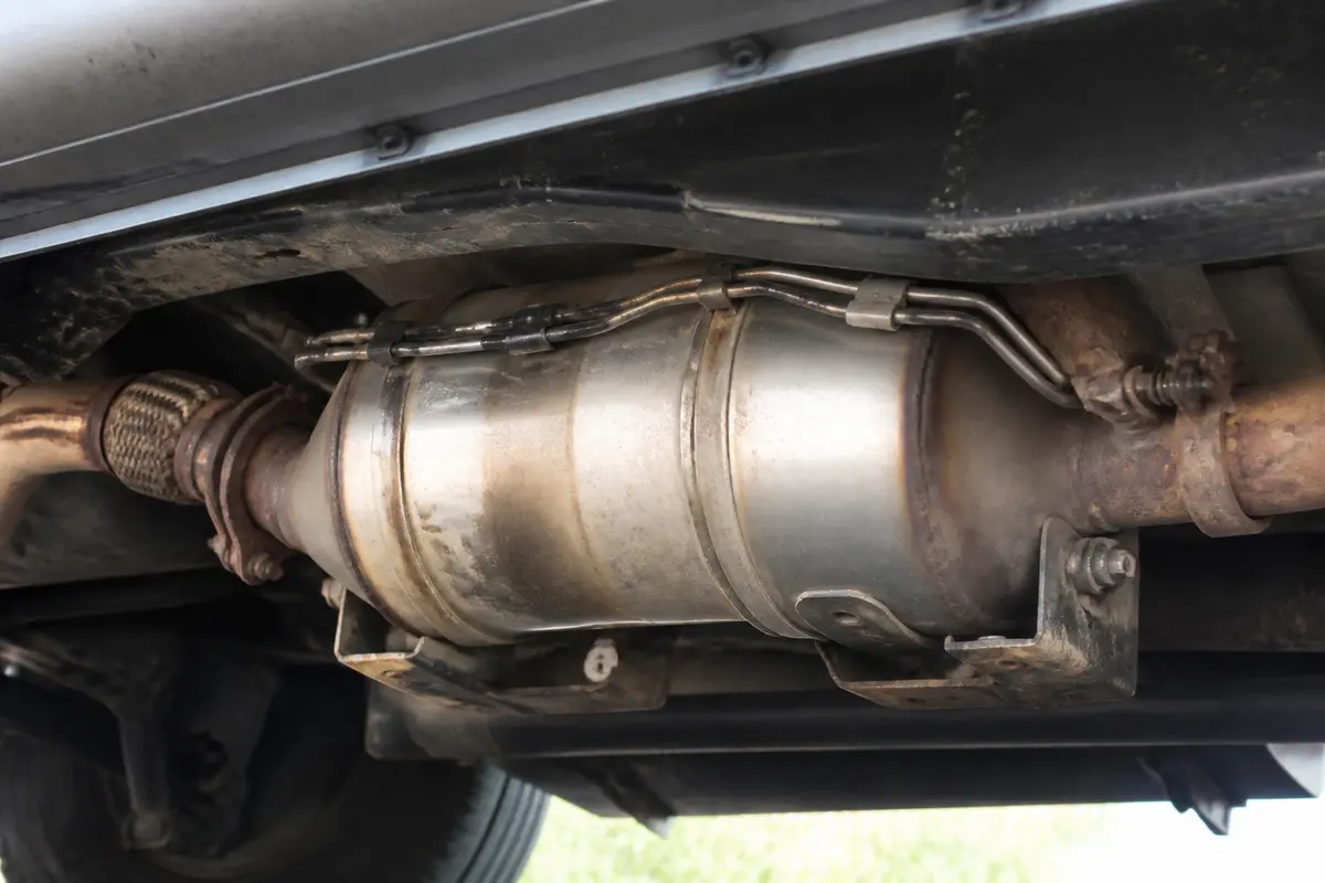 Vue sous un véhicule montrant un pot catalytique métallique attaché à l'échappement.