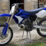 Moto cross bleue 125 YZ de l'année 2000 en extérieur sur béquille.