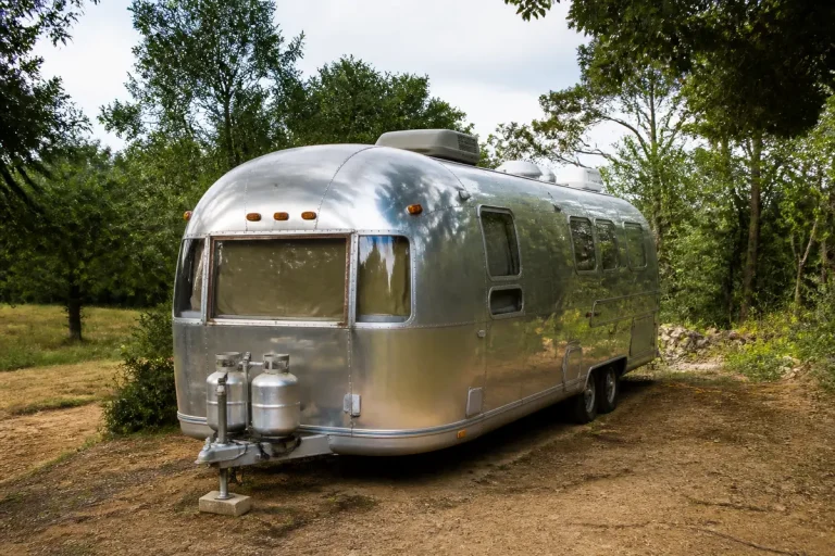 Caravane Airstream d'occasion stationnée dans un cadre verdoyant en plein air et silencieux