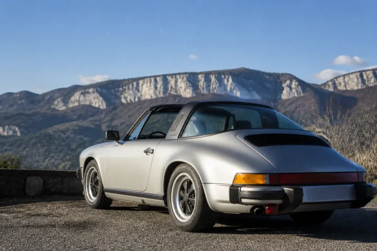 Voiture classique Porsche Targa de 1980 argentée devant des montagnes rocheuses