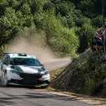 Voiture de course au Rallye du Pays du Gier 2025 sur route sinueuse en forêt