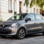 Petite voiture urbaine Renault Twingo grise garée dans une rue calme et arborée