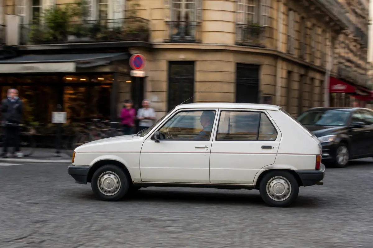 Voiture Citroën Visa blanche roulant dans une rue animée en ville