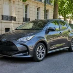 Voiture grise Toyota Yaris hybride d'occasion stationnée dans une rue calme