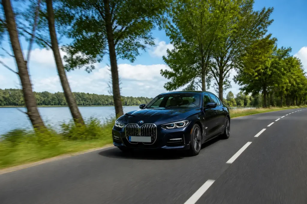 Voiture hybride tousenbagnole.fr roulant sur route bordée d'arbres et rivière proche